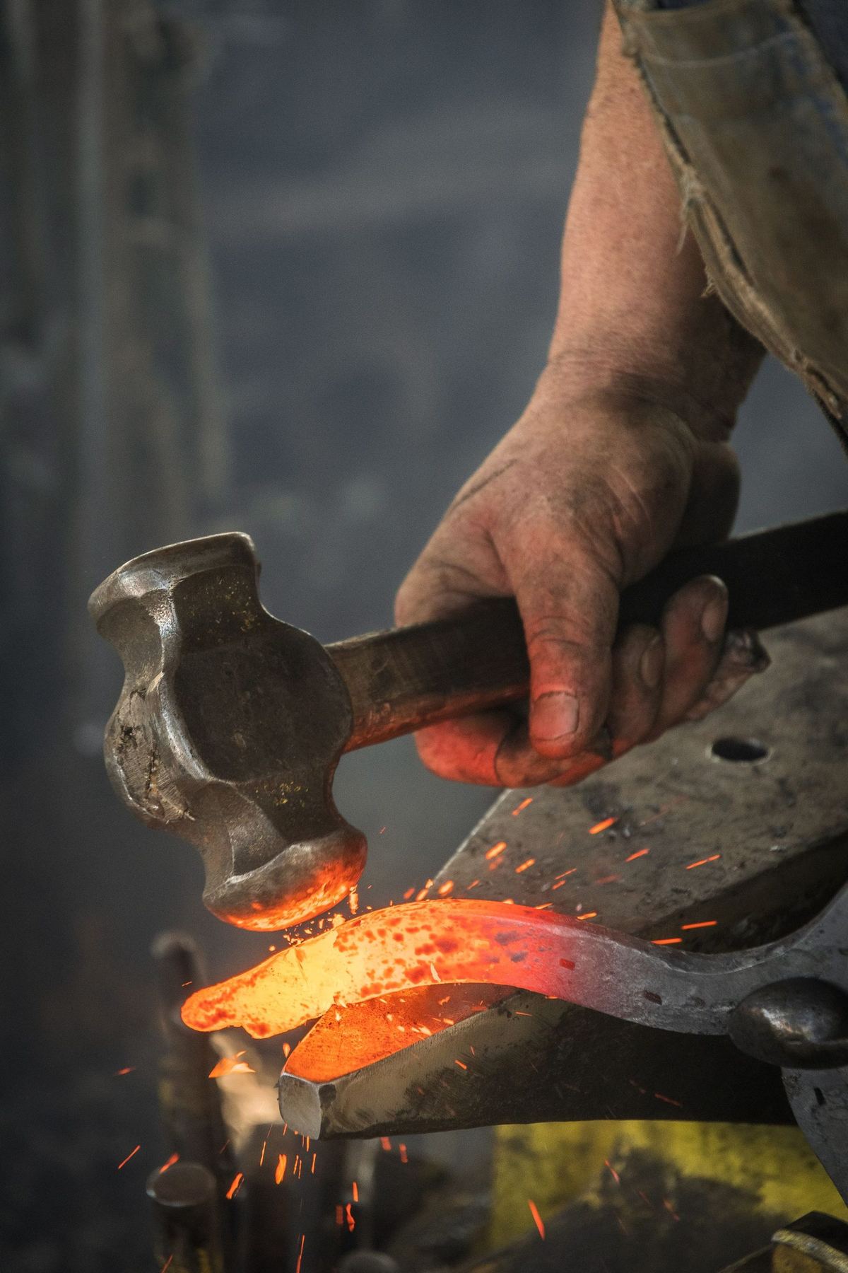 A hammer striking glowing steel on an anvil
